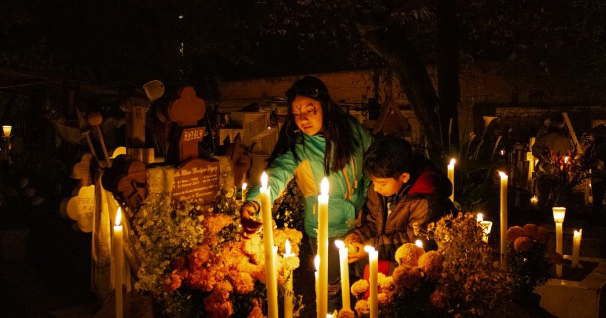 Veladoras y flores durante una visita familiar a un cementerio