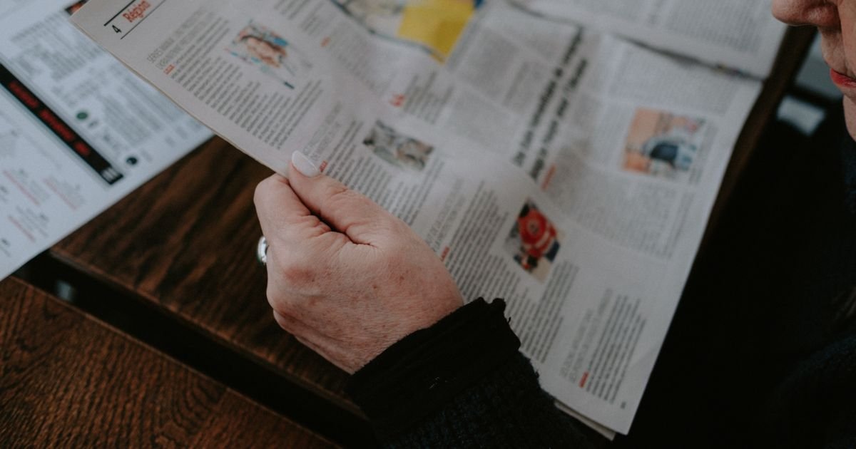 Persona leyendo un periódico en interiores.